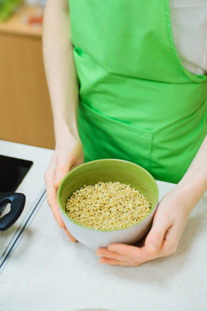 hands of white caucasian woman holds ceramic bowl with pearl barley