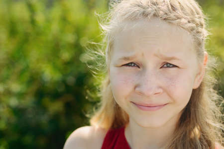 portrait of cute little blonde caucasian girl on green grass backgroundの写真素材