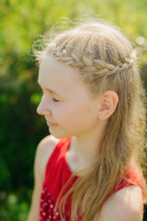 portrait of cute little blonde caucasian girl on green grass backgroundの写真素材