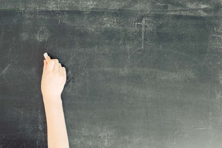 Child's hand with chalk on black chalkboard, stock photo imageの写真素材