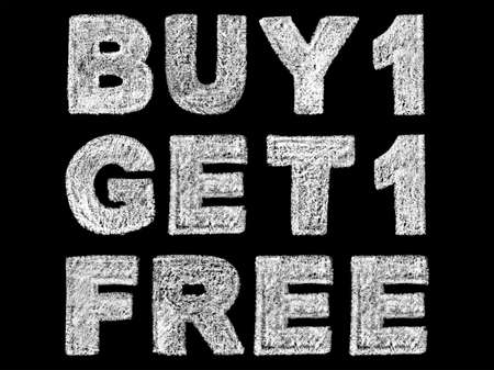 Handwritten white bold chalk lettering buy 1 get 1 free text on black background, hand-drawn chalk phrase, back to school concept, stock photo imageの写真素材