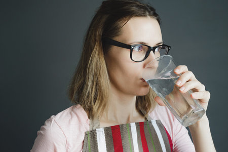 girl in glasses drinks water from glass, close-up portrait of white caucasian woman, stock photo...