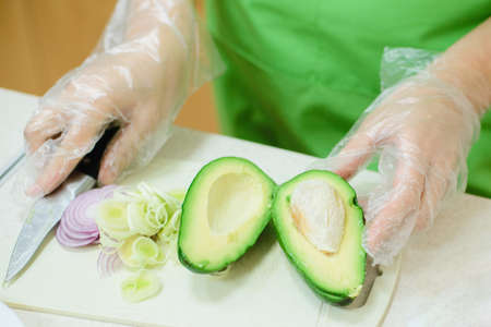 cook cuts avocado to make saladの写真素材