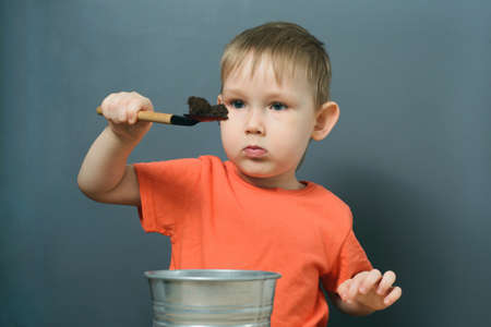 caucasian child boy carefully studies soil lying on scoop, indoors gardeningの写真素材