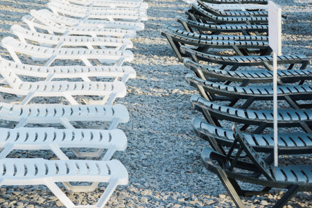 plastic white and black sunbed in row on beach, waiting, start or end, rest out of the tourist...