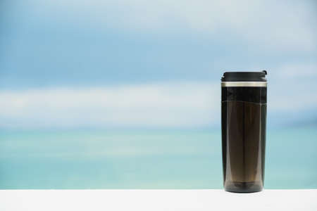 plastic black mug without handle on blurred sea and sky background with copy space, zero waste and my cup please concept, still life mockup or template, horizontal stock photo imageの写真素材