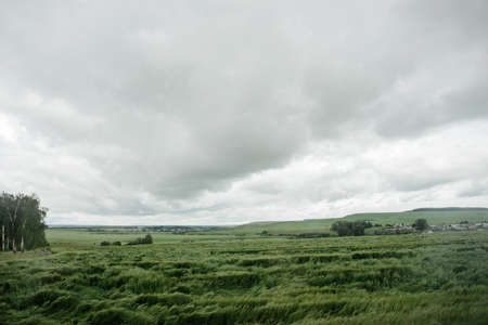 bad weather in summer day, dark dramatic rainy sky clouds over agricultural rural landscape, horizontal stock photo imageの写真素材