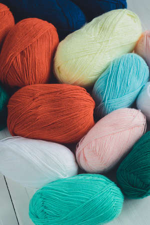 colorful oval acrylicacrylic yarn wool skeins lying on white wooden background, view from angle above, vertical stock photo imageの写真素材