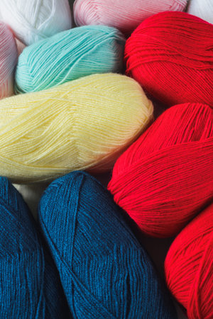 colorful oval acrylic colorful wool yarn thread skeins background, view from angle above, vertical...