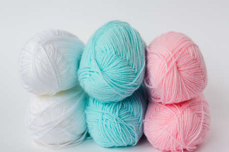 acrylic soft pastel pink, azure and white colored wool yarn thread skeins row on white background, side view, horizontal stock photo image backgroundの写真素材