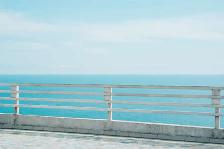 old rusty iron and wooden white fence with sea and sky views, horizontal lifestyle stock photo image backgroundの写真素材
