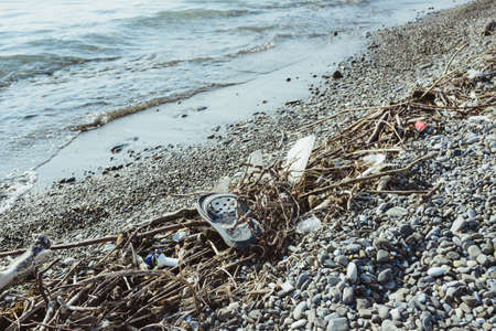 garbage, junk, litter, broken tree branches on pebble shore sea beach, environmental protection concept, horizontal lifestyle stock photo image photography backgroundの写真素材