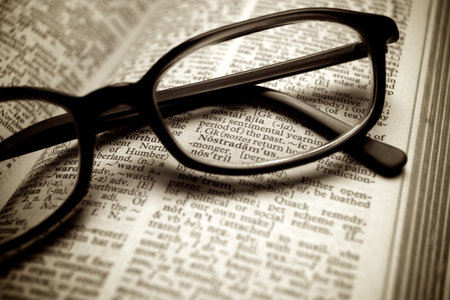 Close-up of old dictionary and black glasses