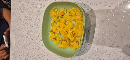 crispy potato chips in a green plate on a white table