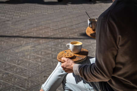 people sitting at the street cafe with coffee and cookie on wooden trayの写真素材