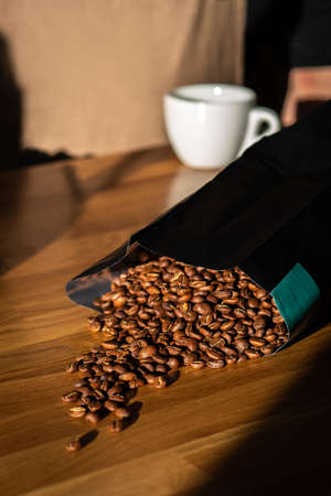 Coffee beans spilled out of the bag on the wooden backgroundの写真素材