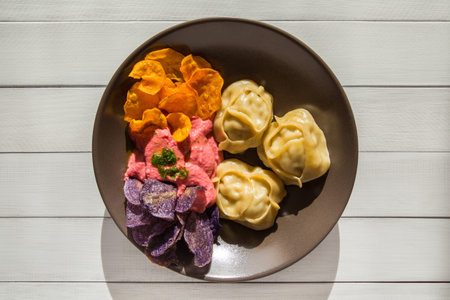 Steamed meat dumplings Manti with beetroot hummus and colored chips of lilac potato and sweet potato chipsの写真素材
