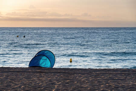 Empty blue tent on the beach. Sunset on the sea coast. Camping on the shore of the ocean.の写真素材