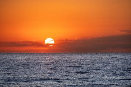 Sun is rising above the calm blue sea.
