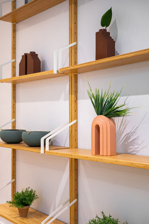 Interior wooden stand with shelves, plants, bowls and decorative elements. Home staging concept....