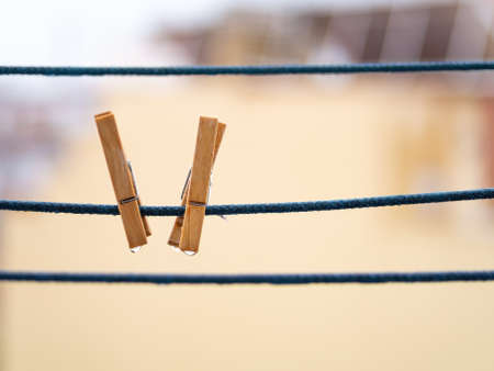 A couple of wooden clothespins on a blue rope with hanging waterdrops after the rain with copy space.の写真素材