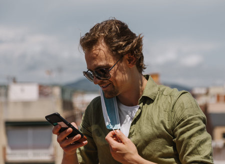 Smiling excited european man taking off protective mask to unblock the phone. End of quarantine, the...