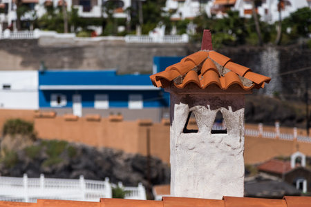 Orange shingle roof with chimney in mediterranean style, buildings at the background.の写真素材