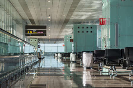 Empty airport lounge area with seats, moving walkway, trash cans and scoreboard.の写真素材