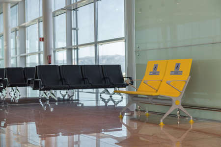 Empty priority seats in international airport reserved for disabled people. Normal and yellow disabled seats in the waiting area before boarding.の写真素材