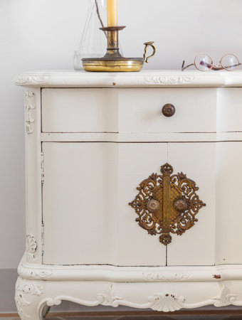 Close-up of vintage wooden bedside table with metal fitment. Candle and glasses for reading for cosy...