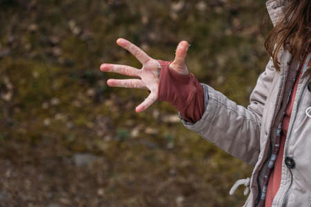Open palm with particles of snow. Wet and cold womans hand in thumbhole jumper during a hiking in spring.の写真素材