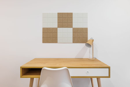 Front view of stylish room interior with modern comfortable workplace. Wooden table with white wall...