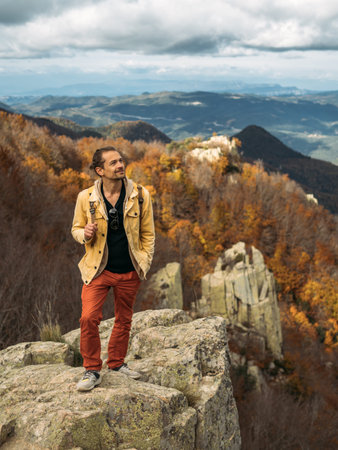 Traveler is standing on high rock, enjoying the view and looking up. Travel and hiking concept in...