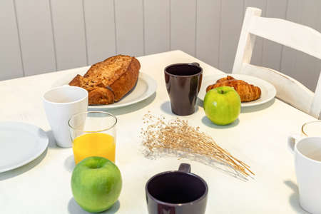 Fresh tasty breakfast served on a white table with croissants, apples and orange juice.の写真素材