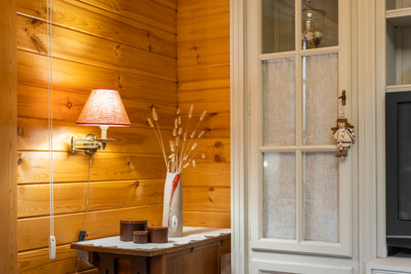 Cozy corner with lamp, vase with flowers and cupboard. Home decor in living room with wooden walls.の写真素材