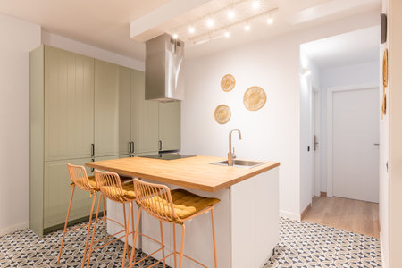 Bright warm kitchen with appliances, wooden island and high chairs in modern apartmentの写真素材