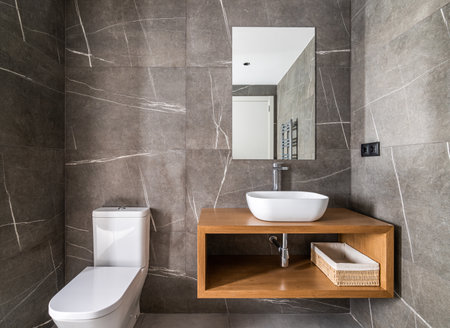 Dressing room with walls made of dark gray marble with white touches, small ceramic oval sink on...