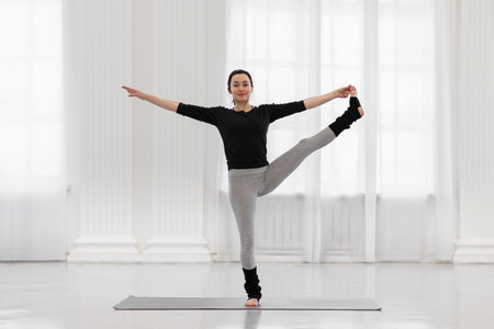 Cheerful young woman doing utthita hasta padagusthasana in the gym while yoga classes. Concept of...