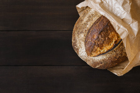 Fresh homemade wheat bread on wooden table in craft package. Flat lay, top view, copy space concept.の写真素材
