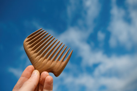 A hand holding natural wooden comb made of pear tree for scalp massage and aroma combingの写真素材