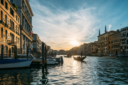 Gondolier on a gondola floats along a canal in Venice in the middle of ancient buildings on an early sunny morning. Beautiful romantic travel concept. Copyspacの写真素材