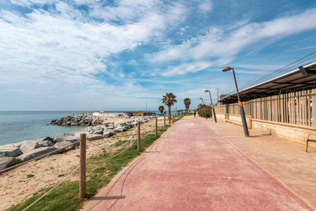 Railway station and road on waterfront by rocky beachの写真素材