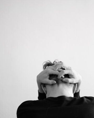 Portrait of a person holding their head in a pose of contemplation or distressの写真素材