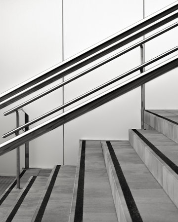 Modern stairway design with sleek metal handrails and contrasting steps in black and whiteの写真素材