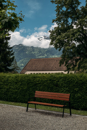 A serene bench in Liechtenstein, offering tranquil mountain views, is a picturesque retreat in the alpine countrysideの写真素材