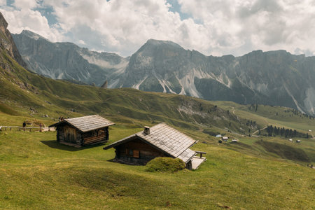 A Serene and Picturesque Alpine Landscape in the Beautiful Dolomites Featuring Charming Rustic Cabinsの写真素材