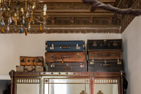 Stacked vintage suitcases on top of a decorated wooden wardrobe in a classic interiorの写真素材