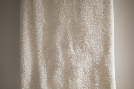 Close up texture of soft white towel hanging against a neutral background in natural lightの写真素材