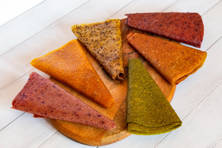 Assorted fruit pastille slices in different colors laid out in circular pattern on wooden board with...