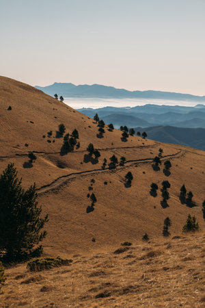 Low rounded hills descending toward hazy ridges and fog-wrapped mountain horizon lineの写真素材